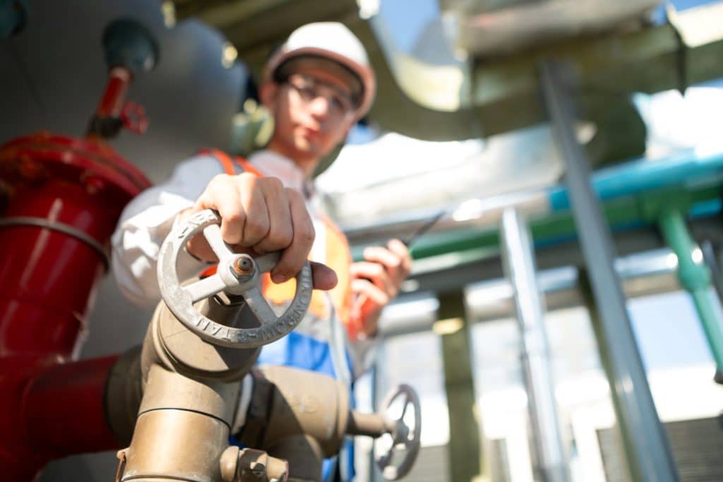 closeup of person's hand adjusting valve on pipe