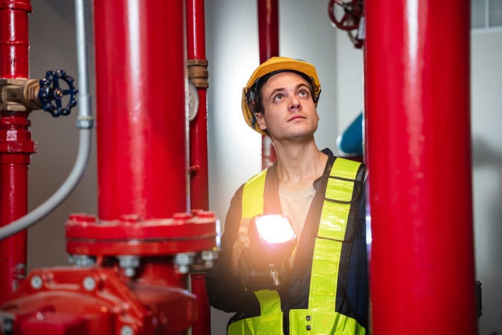 man inspecting fire suppression pipes